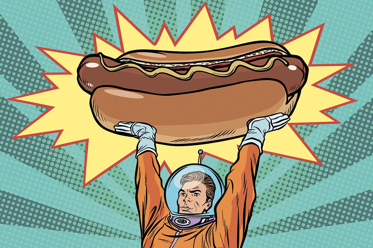Astronaut holds a large hot dog above his head
